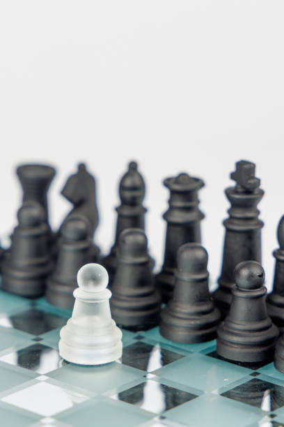 istock A white pawn confronts black chess pieces on a reflective chessboard, symbolizing resilience, leadership, and strategic problem-solving 2203443289