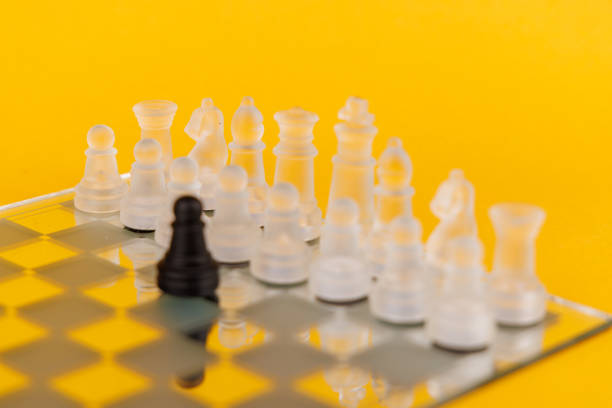 clear glass, transparent chess pieces on a checkerboard, selective focus, closeup, isolated on black