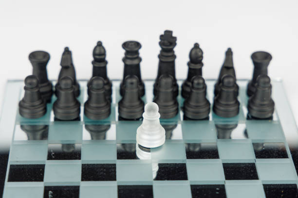istock A lone white pawn stands before black chess pieces on a mirrored board, representing intelligence, courage, and decision-making skills 2203443382