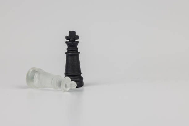 istock Two crystal chess kings, black and white, are displayed on a white background, with one lying down, symbolizing triumph and defeat in strategy 2203443609