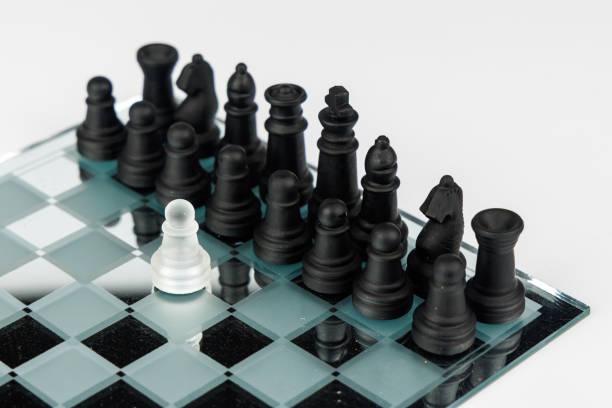 A reflective chessboard holds a dramatic scene with a white pawn against black chess pieces, evoking themes of challenge and strategy