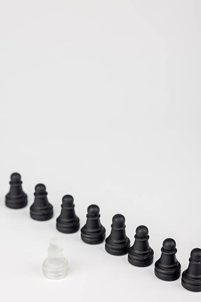 istock A glass chessboard scene where a white pawn faces black pawns. A fallen king suggests leadership struggles, courage, and the impact of decisions 2203444117