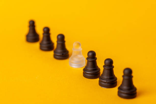 istock A single white pawn disrupts the uniformity of black pawns in a row, visually emphasizing the significance of diversity and individuality 2203444182