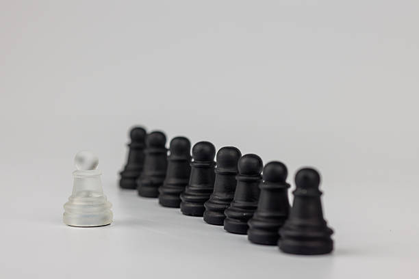 istock A strategic chess scene with black pawns aligned against a white pawn. A fallen king symbolizes leadership and sacrifice. White background enhances contrast 2203444279