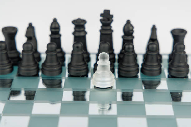 Strategic confrontation shown with a white pawn against black chess pieces on a mirrored board, emphasizing leadership and resilience