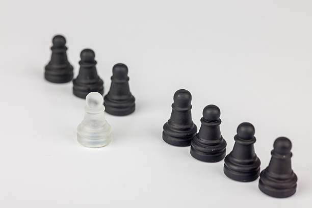 istock A chess scene where a single white pawn faces black pawns. The fallen king in the background highlights the impact of choices and strategic sacrifice 2203444445