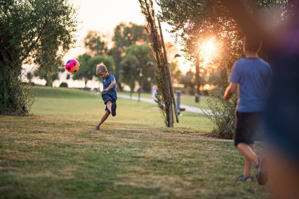 istock Two boys are playing soccer in a park on a summer evening. 2203447497