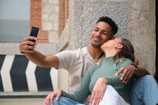 istock Young couple taking a selfie while kissing in the city 2203447706