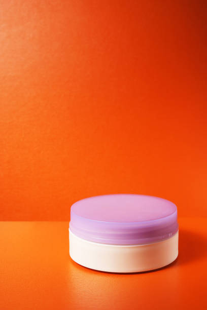 istock white face cream jar with closed lilac lid on orange background. empty jar 2203448159