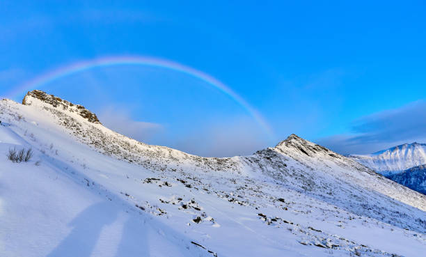 istock rainbow over sbowy montain summit in northeern Norway 2203449170