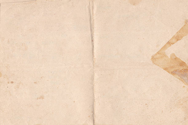 istock Brown old paper texture. Folded parchment paper sheet background with space for text. Vintage worn paper texture 2203450636