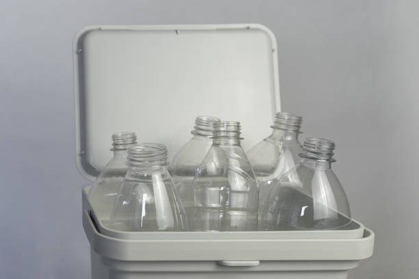 Transparent Plastic Bottles in White Recycling Bin, Eco-Friendly Concept, Against Neutral Background