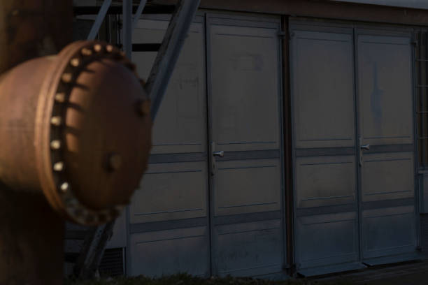 A weathered, rusty pipe is positioned just in front of a building that features large sliding doors for easy access and entry
