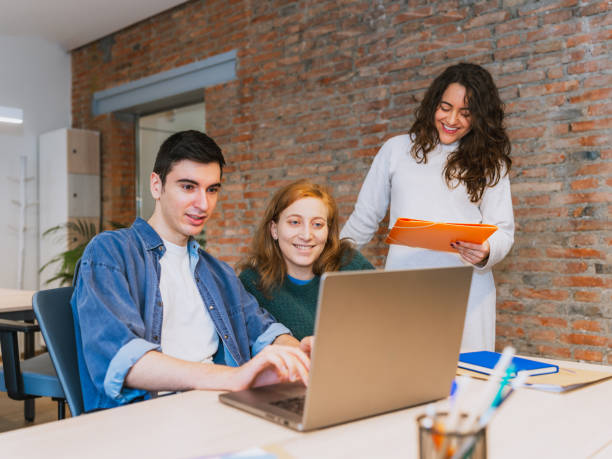 istock Happy Team Collaborating on a Laptop in a Modern Coworking Space 2203456613