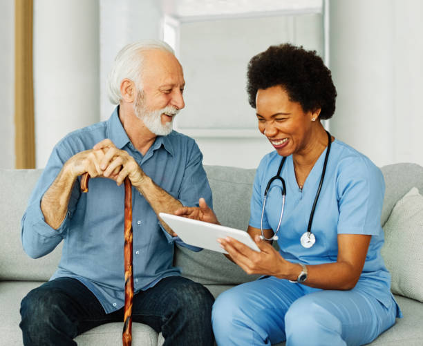 istock nurse doctor senior care tablet computer technology showing caregiver help assistence retirement home nursing elderly woman african american black happy laughing man 2203457542