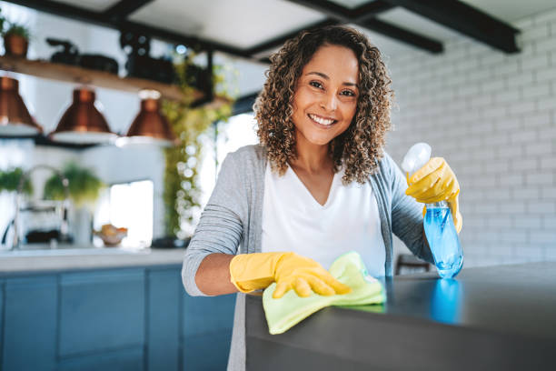 istock A woman cleans the kitchen counter looking at camera 2203460583