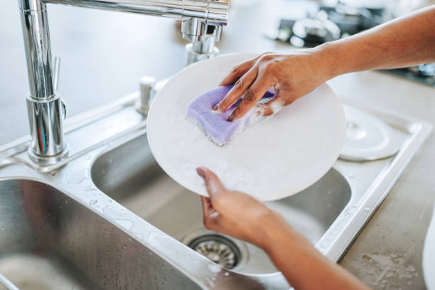 istock Woman washing a plate with a sponge 2203460604