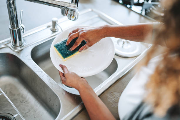 istock Woman washing a plate with a sponge 2203460609