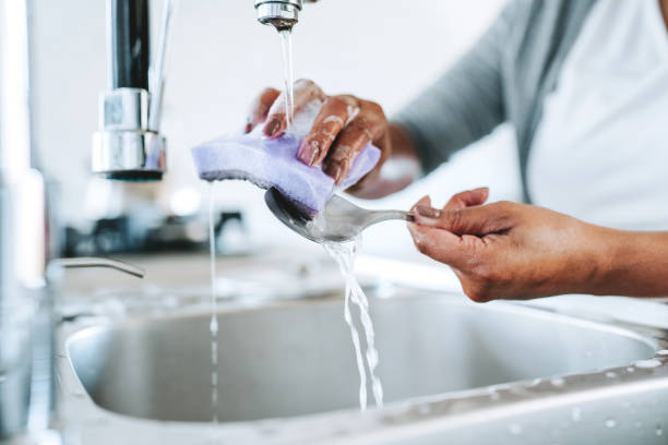 Woman washing cutlery with a sponge