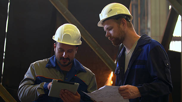 istock Two engineers in hardhat discussing with tablet and blueprint 2203460656