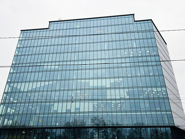 Modern glass office building reflecting the cloudy sky and surroundings