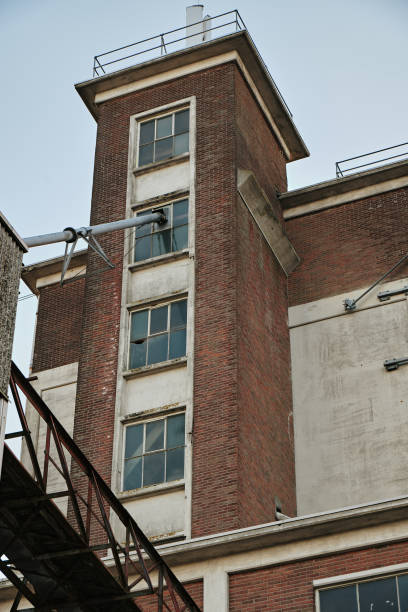A historic grain silo with a red brick facade, weathered concrete details, and broken windows, showcasing industrial decay and urban abandonment.