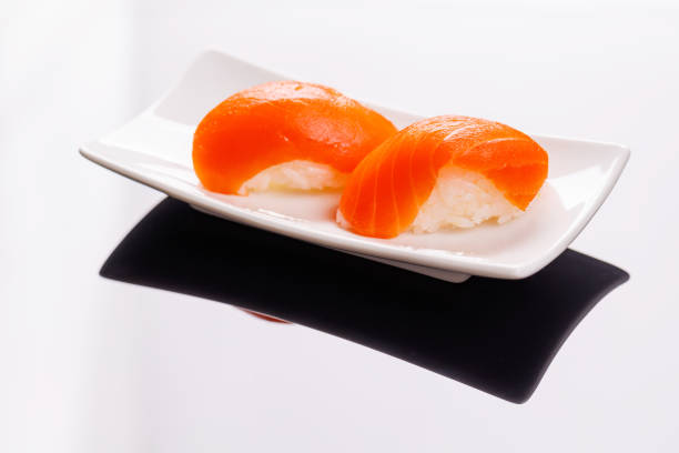 Salmon sushi beautifully arranged on plate, featuring fresh ingredients and vibrant colors, on a clean black background