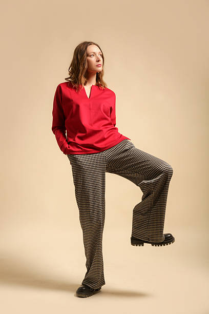 istock Female model wearing houndstooth trousers and red shirt, studio shot 2203467980