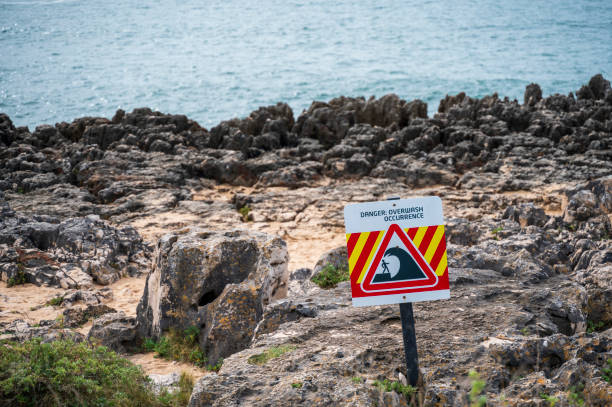 Close up of a danger sign, Overwash danger, unstable cliffs keep clear, with the cliffs in the background on ocean coast.