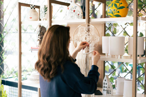 istock Shopkeeper arranging macrame dream catcher on shelf display 2203471847