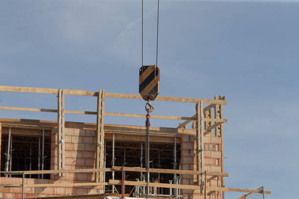 A large crane is lifting a brick building at a bustling construction site, showcasing the teamwork and engineering involved in this project