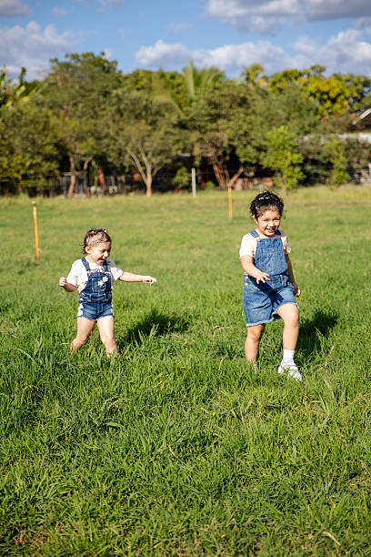 Happy sister girls running through a field together in El Salvador