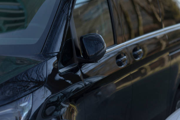 istock A closeup of a black car reflecting trees in its window 2203477225