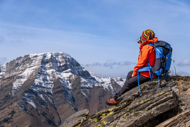 istock A female climber is watching the landscape while drinking hot coffee or tea from the rough, extreme terrain at the summit of a mountain. 2203478963