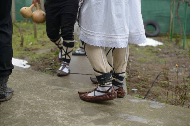 Men dressed in Bulgarian folk attire gather before performing the Kukeri ritual, featuring distinct strapped footwear and woven leggings used to ward off evil spirits and celebrate local heritage