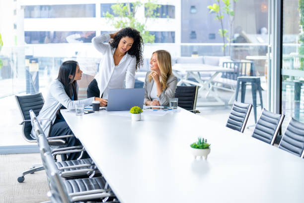 istock Three business  women meeting. They are discussing something while looking at a laptop computer. 2203480121