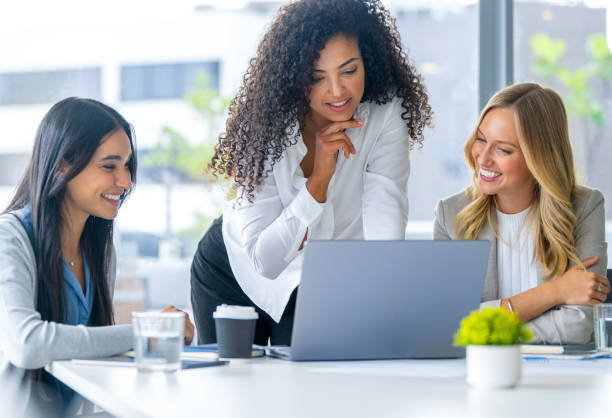 istock Three business  women meeting. They are discussing something while looking at a laptop computer. 2203480126