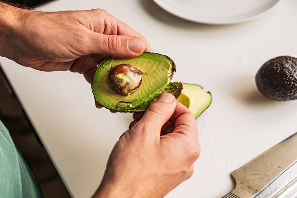 istock Man peeling a ripe avocado on the countertop 2203480225