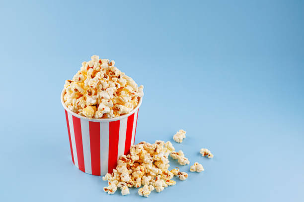 istock Classic red striped popcorn cardboard cup on blue background 2203481920