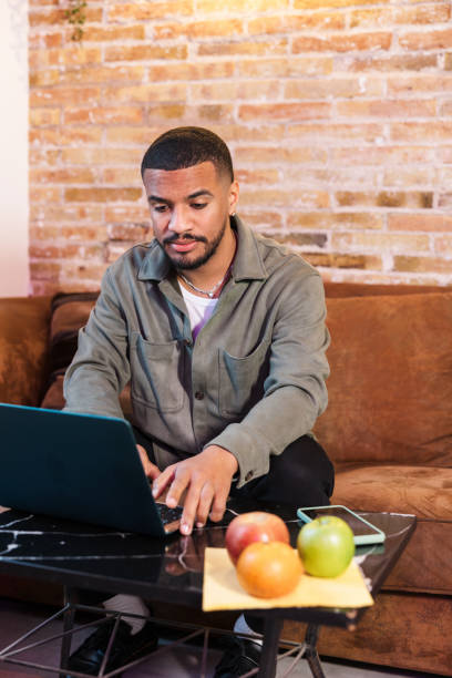istock Focused young man working from home on laptop with healthy snack 2203483319