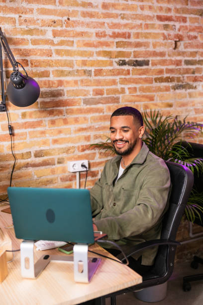 istock Young businessman smiling and working on his laptop in a modern office 2203484235