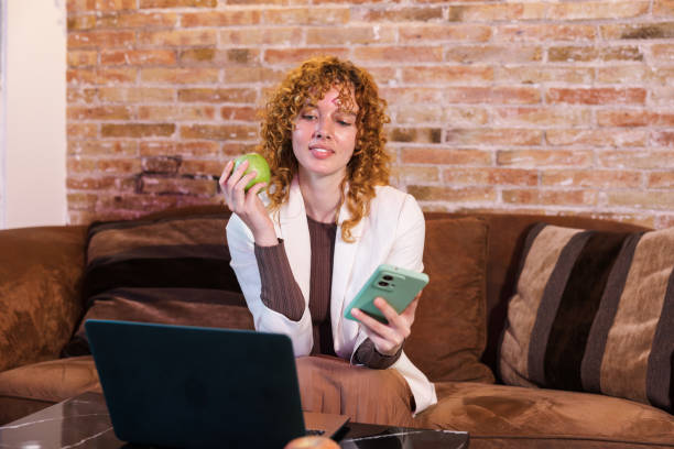 istock Freelancer working from home eating an apple and browsing smartphone 2203485006