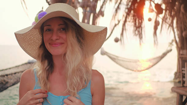 istock Attractive blonde straw hat posing and looking at camera on beach 2203488269