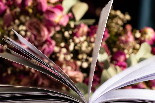 istock Open book on wooden table at home with dry roses bouquet 2203488850