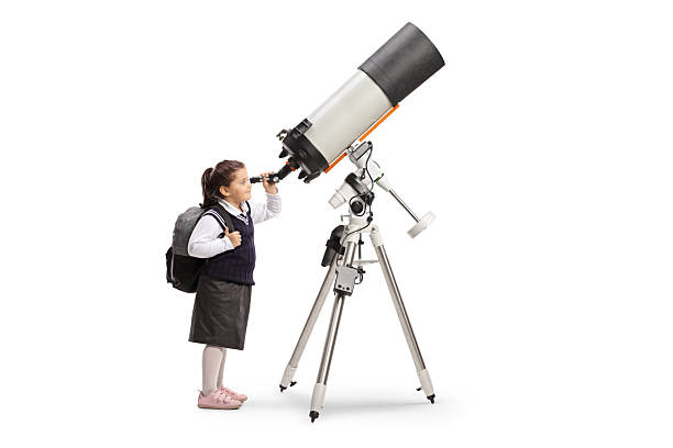 Schoolgirl in a uniform observing the sky through a telescope isolated on white background