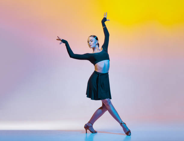 istock Graceful dancer in black clothes dances Latin American dances on a bright gradient background. 2203495026