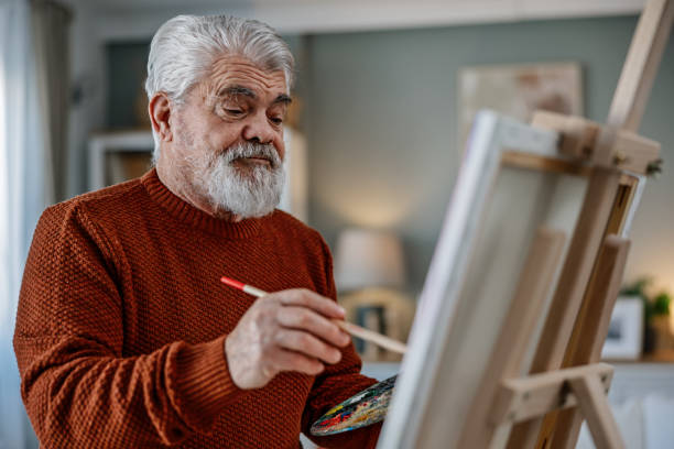 istock Senior artist painting on canvas at his home studio 2203495646
