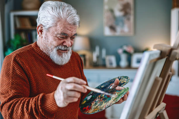 istock Senior artist painting on canvas at his home studio 2203495653