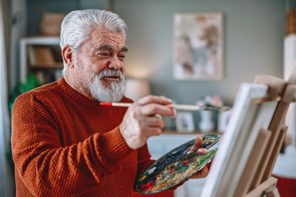 istock Senior artist painting on canvas at his home studio 2203495654