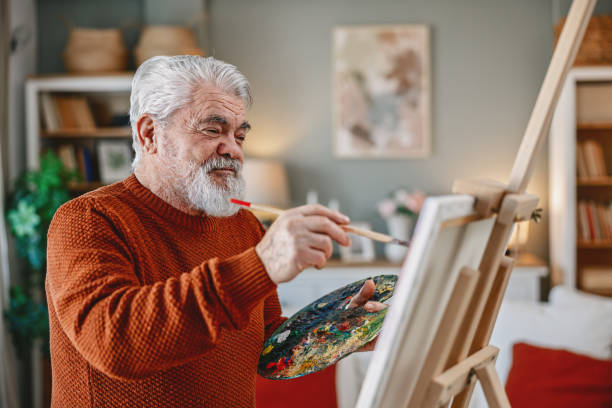 istock Senior artist painting on canvas at his home studio 2203495706